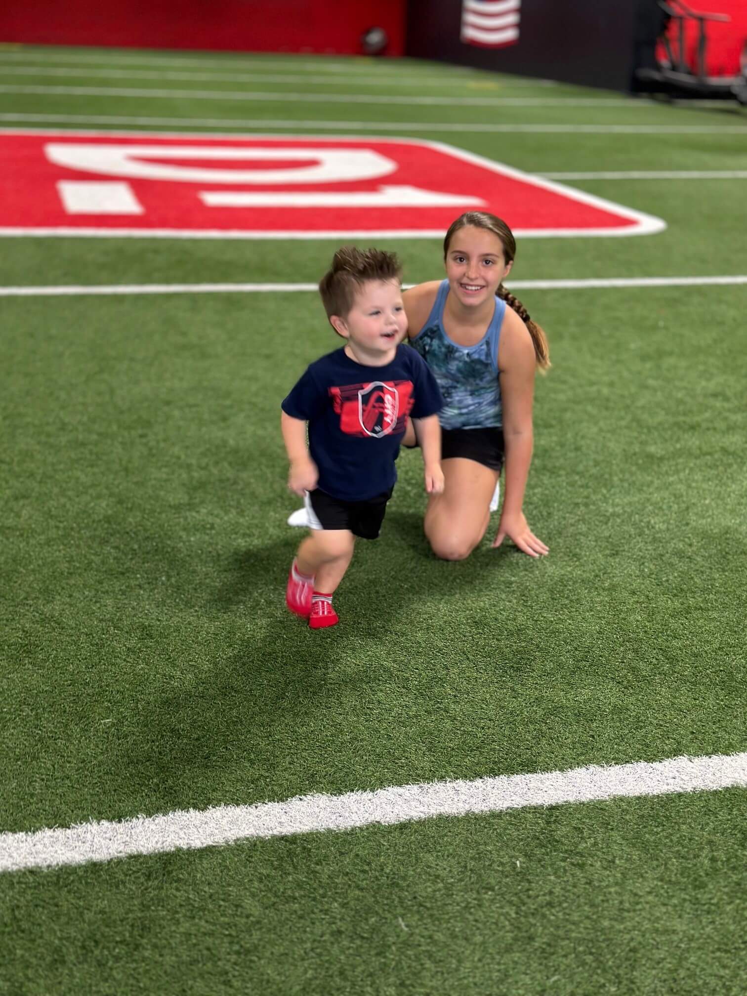 young girl posing with a younger boy on the indoor field at D1 Training St. Louis West
